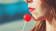 © tashechka - Girl enjoys a red lollipop while standing outside in bright sunlight