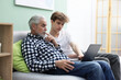 © New Africa - Teenage boy helping elderly man learn how to use laptop on sofa at home. Modern technology for seniors