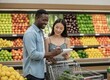 © KIMOG - Happy African American Man Looking at Asian Woman Holding Notebook While Grocery Shopping