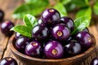 © miss irine - Close-up of fresh purple Jaboticaba fruits in wooden bowl. Dark berries with green leaves on rustic table background. Exotic Amazonian produce healthy food.