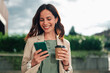 © Zamrznuti tonovi - Smiling businesswoman checking smartphone on a coffee break outdoors, enjoying communication and casual business lifestyle