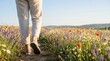 © MT - Young woman walking through a vibrant summer wildflower meadow at sunset representing freedom mindfulness and connection with nature