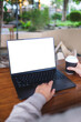 © Farknot Architect - Vertical mockup image of a woman working and touching on laptop computer touchpad with blank white desktop screen in cafe