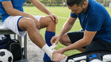 Sports therapist taping soccer player's ankle on sideline