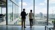 © Mia - Business people discussing renewable energy solutions while looking at solar panels and wind turbines from high rise office window