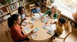 © Alva - A diverse group of happy children and an adult woman enjoy a creative watercolor painting session around a round table in a bright classroom.
