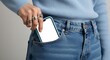 © Master Mockup Lab - Woman in light blue sweater and denim jeans placing smartphone into pocket close-up