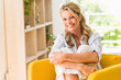 © Westend61 - Portrait of smiling mature woman relaxing in armchair at home