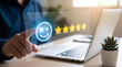© Rahman - Customer experience concept, hand touching a virtual screen with a happy face icon and five stars rating for top rated service