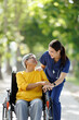 © David - Caregiver assisting senior woman in wheelchair outdoors, showing support, compassion, and shared happiness during an assisted living or home care walk in nature