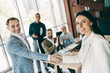 © deagreez - Confident business professionals shaking hands in modern office with teamwork and collaboration in focus