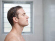 © Someone Cooked Here - Handsome young white man enjoying a refreshing shower in side profile in a modern bathroom for grooming and wellness advertising