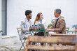 © Guirado - three business people having a meeting for a briefing outside the office with laptop and tablet