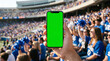 © Hiskia - Capturing the intense energy of a crowded sports arena while holding a glowing green screen smartphone for digital content integration and mockup.