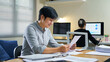 © Stella 16 - businessman sitting looking at graph chart report documents in her hands while female colleague in black suit sitting nearby her working desk