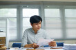 © Stella 16 - businessman sitting looking at graph chart report documents in her hands while female colleague in black suit sitting nearby her working desk