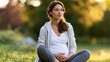 © Mary - Pregnant woman sitting outdoors in park at sunset