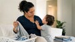 © Maryia - Busy mother trying to finish chores while responding to a toddler need for closeness, expressing realistic domestic life and the nonstop rhythm of early motherhood.