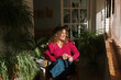 © JORGE PONZ/Stocksy - Woman enjoys time with houseplants in a bright balcony space