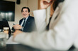 © Maskot - Smiling male business expert sitting with smart phone in meeting room at office