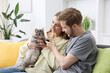 © New Africa - Couple with their cute cat on sofa at home