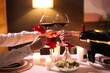 © New Africa - Date. Couple clinking glasses of red wine at table indoors, closeup