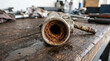 © Len_mik - Close up of reddish rust and scale inside a metal pipe. Corroded tube with heavy oxidation on a wooden workbench