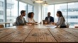 © Masque - Colleagues discussing ideas in a blurred office meeting with focus on a textured wooden table.
