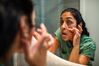 © Marko Geber - Woman examining dark circles in bathroom mirror at home