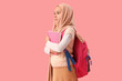 © Pixel-Shot - Little Muslim girl in hijab with school backpack and books on pink background