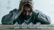 © PixelPulse Creative - Stressed man sitting at a wooden table with miniature white houses, concept of mortgage debt, housing crisis, and financial struggle