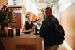 © Maskot - Smiling female receptionist speaking with male freelancer using kiosk at shared workspace front desk