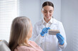 © New Africa - Doctor showing dental implant color chart to woman in clinic