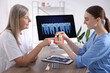 © New Africa - Doctor consulting woman regarding dental implantation at desk in clinic