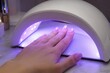 © Anzhelika - Woman dry gel polish on nails in UV lamp. Manicure equipment for nail drying at beauty salon. Professional cosmetic procedure for female hand care. Modern styling and fashion concept.
