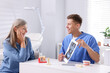 © New Africa - Doctor showing teeth scan and dental implant models to senior woman in clinic
