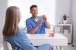 © New Africa - Doctor consulting woman regarding dental implantation at desk in clinic