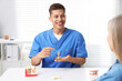 © New Africa - Doctor consulting woman regarding dental implantation at desk in clinic