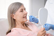 © New Africa - Doctor choosing dental implant color with woman at clinic, closeup