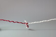 © Hanna - Red and white threads tied together with a knot. Minimal concept of connection, unity, relationships, trust, problem solving, and strong bonds