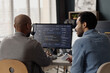 © Seventyfour - Medium shot of two middle aged men reviewing software code on desktop monitor in information technology office, collaborating on debugging and team workflow. For IT services marketing