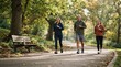 © Justlight - Three adults of mixed ages power-walking along a tree-lined park path, wearing running shoes, breathable jackets, and fitness watches, with a bench, water bottle, and morning sunlight, showing steady