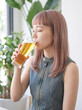 © SHIN-Y - 明るい部屋の中でビールを飲む若い女性