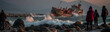 © pattozher - Shipwreck Survivor: A dramatic scene unfolds as a distressed vessel battles rough waves near a rocky shoreline, with a group of onlookers witnessing the perilous situation.