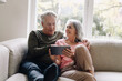 © Westend61 - Happy senior couple relaxing on couch at home using tablet