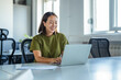 © Miljan Živković - Young asian woman smiling while working on laptop