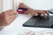 © Aditiya - A view of a hand making a transaction with a credit card and a laptop. Business and finance concept.