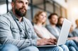 © whitestorm - Diverse group of people attentively listening during a presentation or meeting, focused on a laptop.