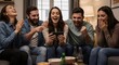 © Flash memory - Group of happy young men and women cheering and laughing while watching something on a smartphone at a home party. Friends enjoying social media content, movie or game.
