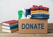 © Rahela - Cardboard box with donated clothes, toiletries, and books on wooden table